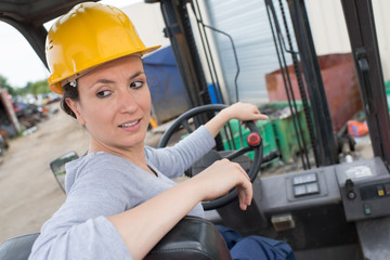 woman reversing forklift truck in scrapyard