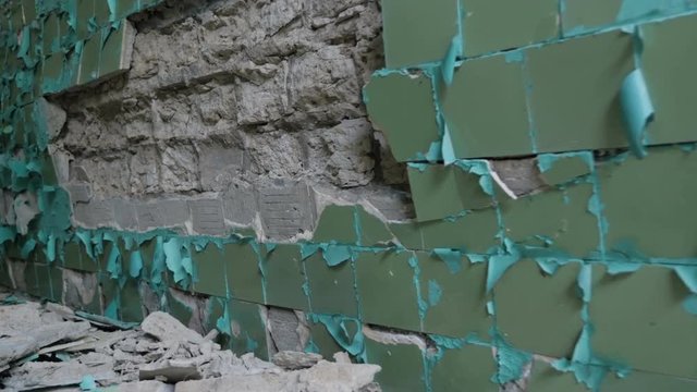 View of cracked ceramic tiles falling off from the wall, closeup
