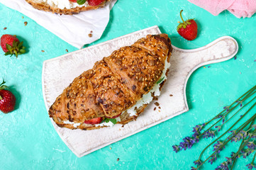 Cereal croissants with cream cheese and fresh strawberries. Useful breakfast. Proper nutrition. French traditional dishes.
