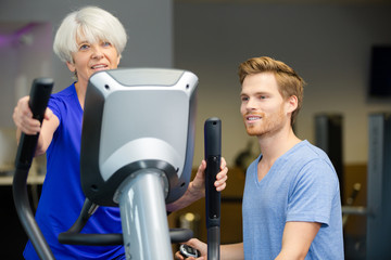 senior woman and trainer smiling at camera in fitness studio