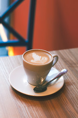 Cappuccino cup on the table in coffee shop background, vintage tone