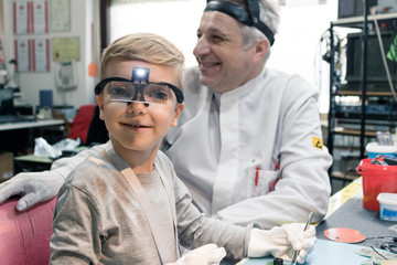 Little student working on school science project with his teacher.