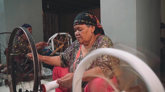 Mature indonesian women using spinning wheel indoors in Pekalongan, Indonesia