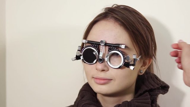 a portrait of a teenager who checks the vision with the help of visionimetry, the girl wears special glasses in which the lenses are gradually changed to determine visual acuity