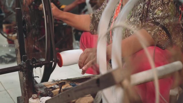 Mature indonesian women using spinning wheel indoors in Pekalongan, Indonesia