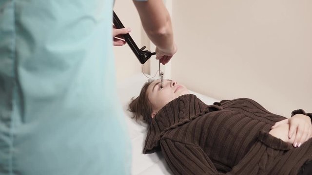 the teenager came to the polyclinic to treat the eyes, the pupil was directed to the equipment, the nurse was nearby and was conducting the procedure