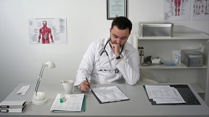 Thinking out loud. Thoughtful young bearded doctor in medical cabinet.