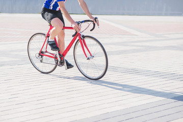 Naklejka premium Man in sportswear and a helmet rides a bicycle in the city. Cyclist rides a red bike on a square with a pavement.