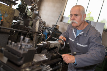 Senior worker using workshop equipment