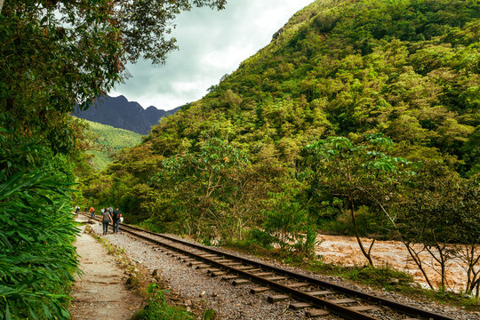 Group of backpackers walk towards Machu Picchu on the railway tracks along the Vilcanota River (Urubamba)