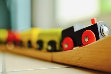 a wooden toy train with colorful wagons moving forward and climbing up the wooden rails 