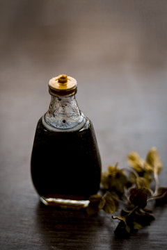 Ayurevedic essence or oil of holy basil or tulsi in a transparent bottle with some fresh bright basil leaves on wooden surface used in many treatments and home remedies related to cough, and fever.