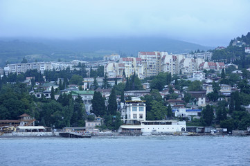 View of the town Gurzuf: sea front, beach, buildings and mountains in the fog. June 10, 2017. Gursuf, Crimea