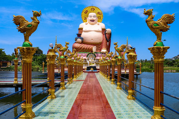 Wat Plai Laem temple with giant fat laughing Buddha statue and golden rooster statues in foreground, Koh Samui, Thailand