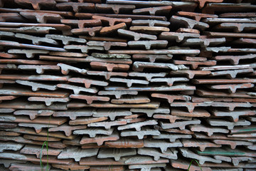 Bales ceramic shingles for roofing. Stack of old ceramic roof tiles, textured background.