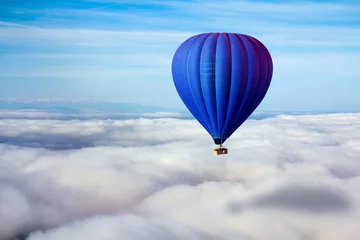 Foto op Plexiglas Ballon Een eenzame blauwe luchtballon zweeft boven de wolken. Concept leider, succes, eenzaamheid, overwinning