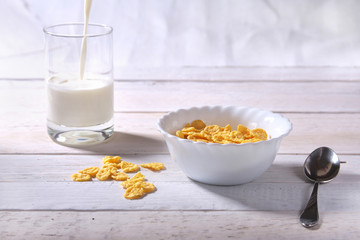 Corn Flakes cereal in a bowl and glass with milk. Morning breakfast.