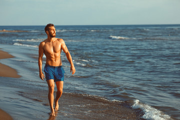 Fototapeta na wymiar Handsome young man having fun on the beach by the sea