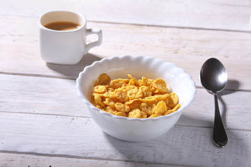 Corn Flakes cereal with milk in a bowl and cap with espresso coffee. Morning breakfast.