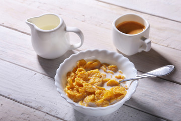 Corn Flakes cereal in a bowl, glass with milk and cap with espresso coffee. Morning breakfast.