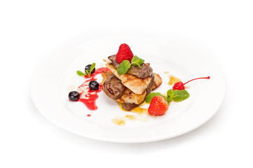 The fried juicy pieces of fillet and liver in an environment of berries of strawberry of raspberry and bilberry, with mint leaves