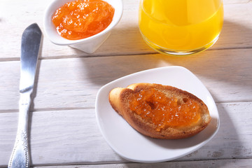 Morning Breakfast set with orange jam on bread toast and juice in glass.
