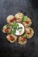 Traditional Uzdek manti steamed with mincemeat and tomato paprika salad as top view on a plate