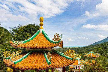 Fototapeta premium Traditional Thai decorated Buddhist temple on a mountain with ocean in the background and jungle in the foreground, Chinese Temple, Koh Phangan, Thailand