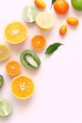 Fruit background. Colorful fresh citrus fruit on a light pastel pink background table. Orange, tangerine, lime, kiwi. Flat lay, top view, copy space 