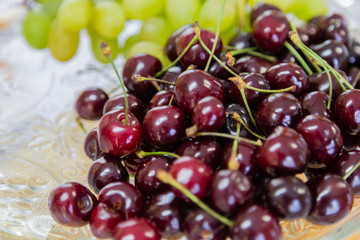 Close up of pile of ripe cherries with stalks and leaves. Large collection of fresh red cherries. Ripe cherries background