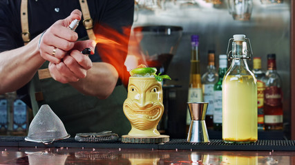 The bartender sets the cocktail on fire