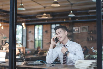 Businessman Using Laptop At Desk In Busy Office