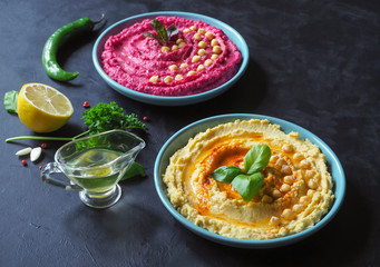 Different kinds of traditional hummus on the black table.