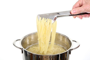 Wyjmowanie gotującego się makaronu spagetti z metalowego garnka.