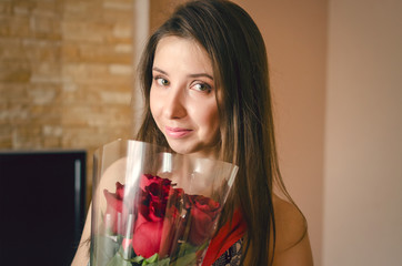 Happy young woman with bouquet of red roses flowers.