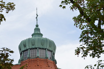 Old copper dome with a cloudy sky and tree tops