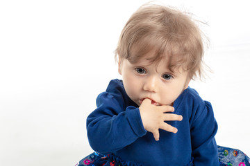 Portrait of happy baby girl 1 year old with blue eyes and dress posing in studio. White Background. Concept Happiness.