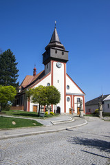 Fototapeta na wymiar Church of St. Wenceslas in town Svetla nad Sazavou, clock tower, greenery and blue sky