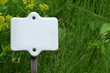 White ceramic sign on grass background with space for text