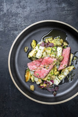 Modernes gegrilltes dry aged Filet Streak aufgeschnitten mit Spargel und Kartoffelsalat als Draufsicht auf einem Teller  