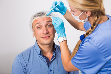 Female doctor is doing injection to patient in skin of face