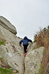 Un jeune enfant fait de l'escalade dans les rochers sur la côte bretonne