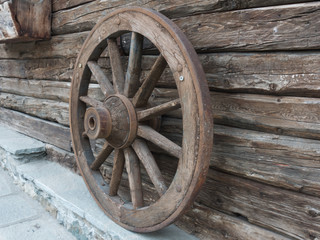 Fototapeta na wymiar Antique wooden wheel of carriage isolated on an old wall