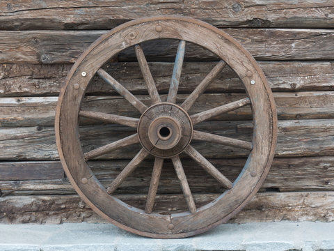 Antique wooden wheel of carriage isolated on an old wall
