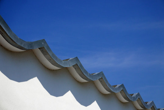 Detail of a white facade and a wavy roof