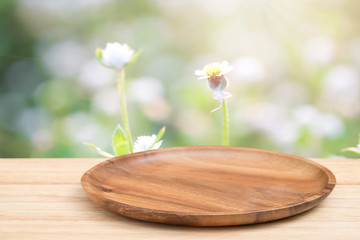 Empty wooden tray on perspective wooden table on top over blur flower background. Can be used mock up for montage products display or design layout.