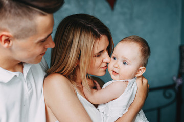 Young parents hugging and kissing little daughter