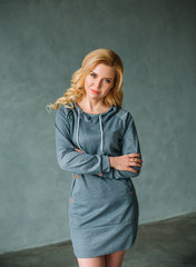 The blond girl is dressed in casual clothes. Woman posing against the backdrop of an interior in loft style. Fashion style