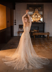 A blonde girl with an elegant styling on her hair, dressed in a luxurious, lush, golden, sparkling...