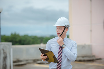 smiling young architect or engineering builder in hard hat with tablet over group of builders at...
